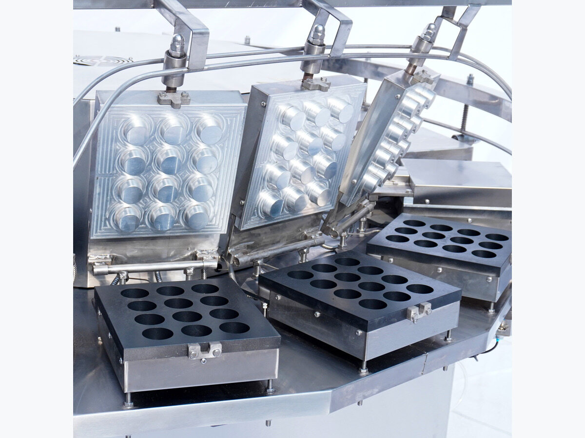 Open round-shell mould plates on a rotary machine.